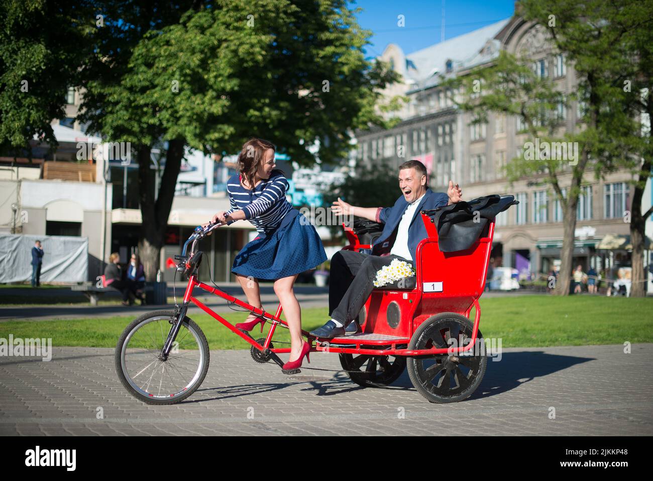 Ein schönes junges Paar, das an einem hellen Tag ein großes Fahrrad in der Stadt fährt - Konzept der Liebe Stockfoto