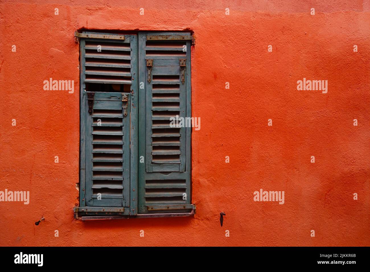 Eine Nahaufnahme eines alten Fensters und einer orangefarbenen Wand Stockfoto
