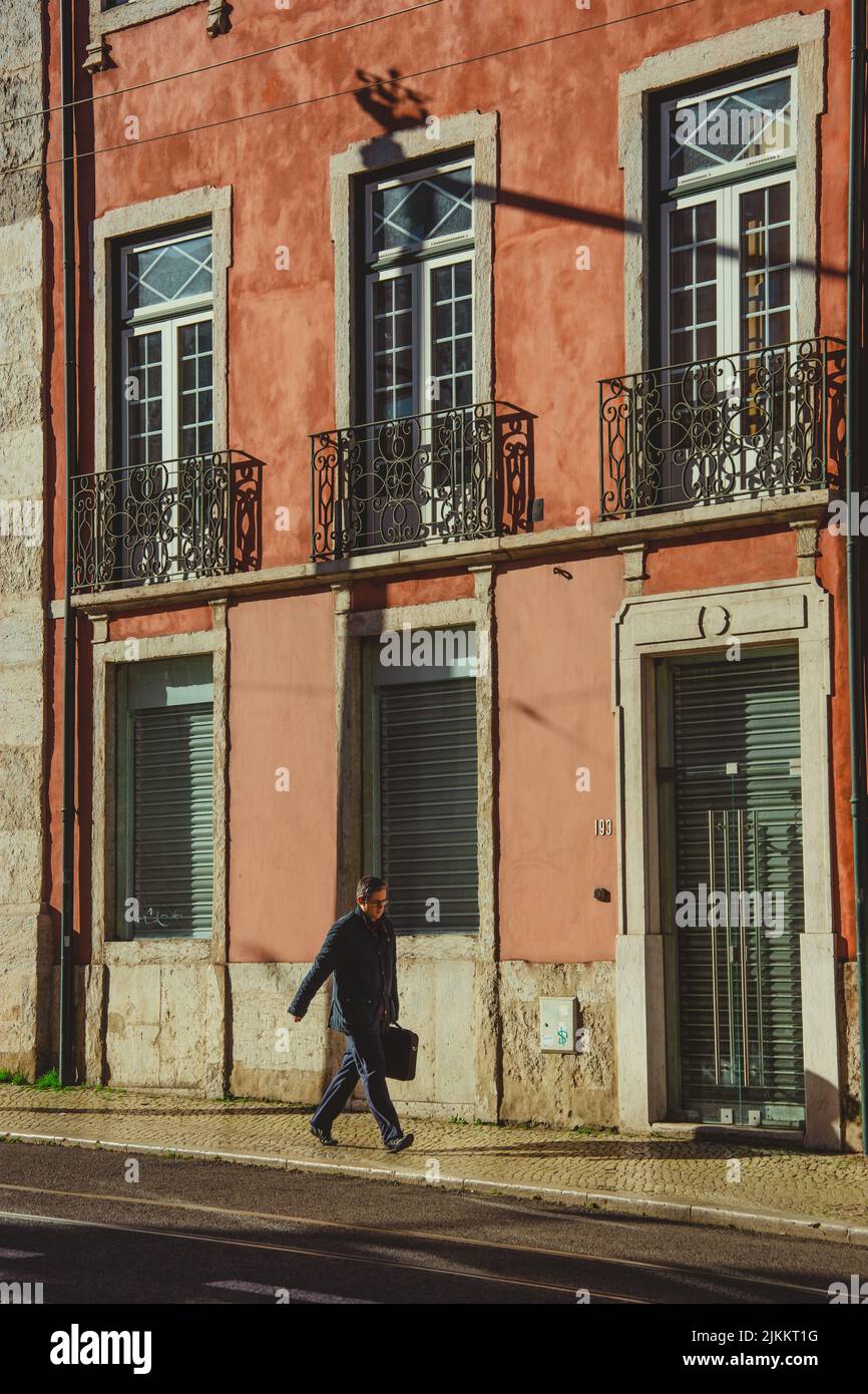 Eine vertikale Aufnahme eines Mannes, der mit einer Aktentasche unterwegs ist, um auf einer Straße zu arbeiten Stockfoto