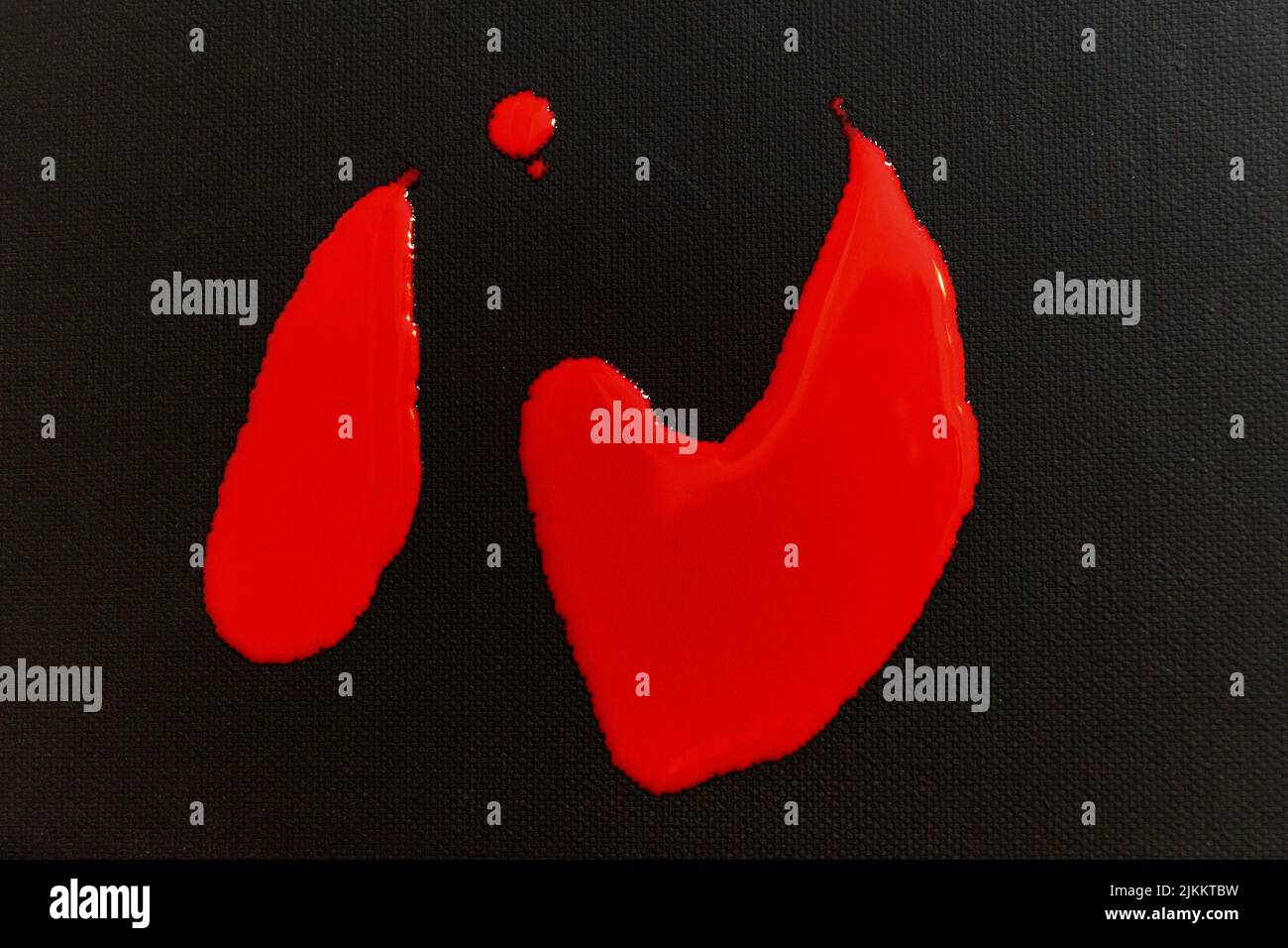 Die rote Farbe fällt auf eine schwarze Leinwand Stockfoto