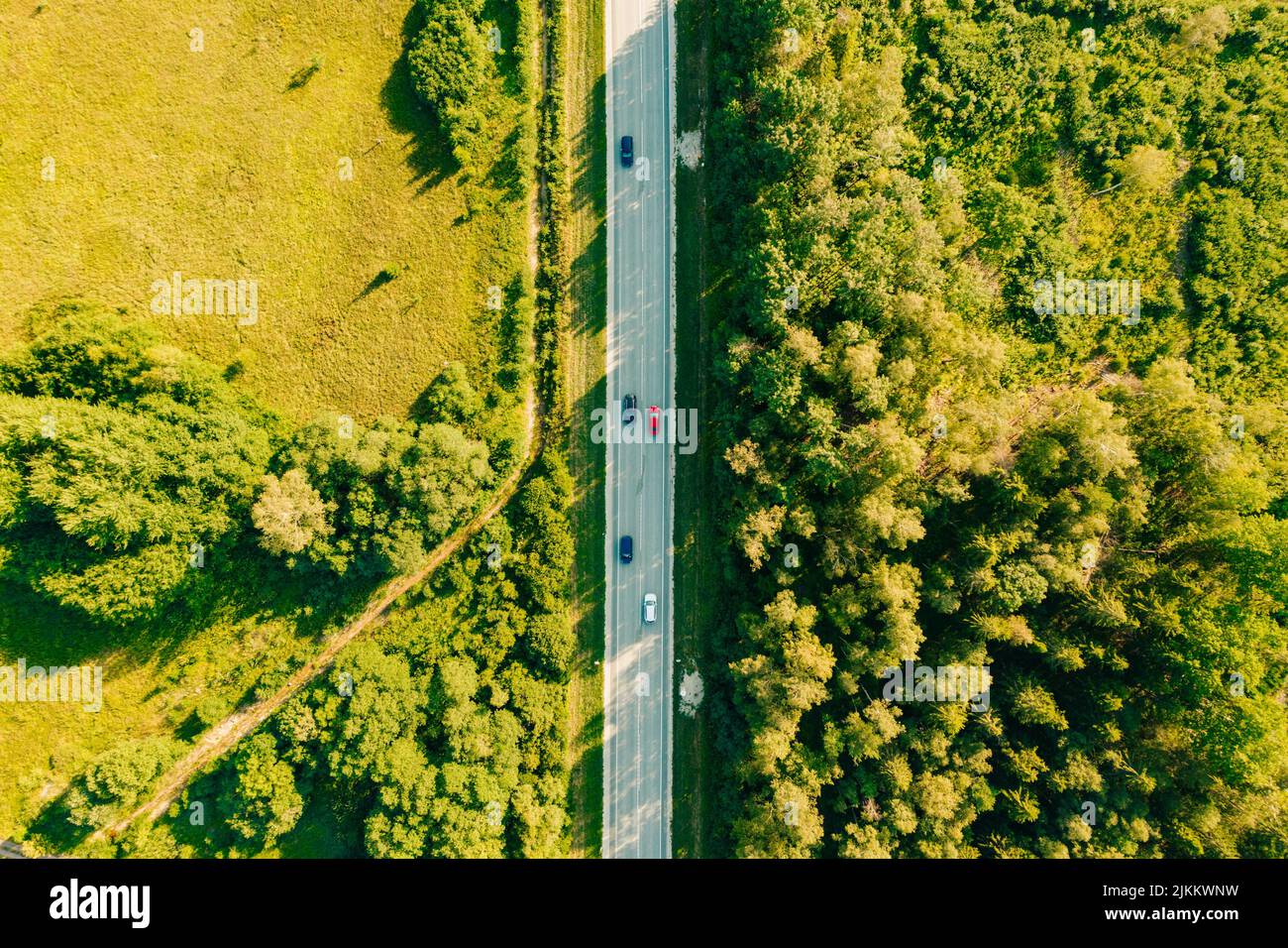 Eine Luftaufnahme von Autos auf einer Autobahn tagsüber mit einem grünen Feld und einem Wald von rechts und links Stockfoto