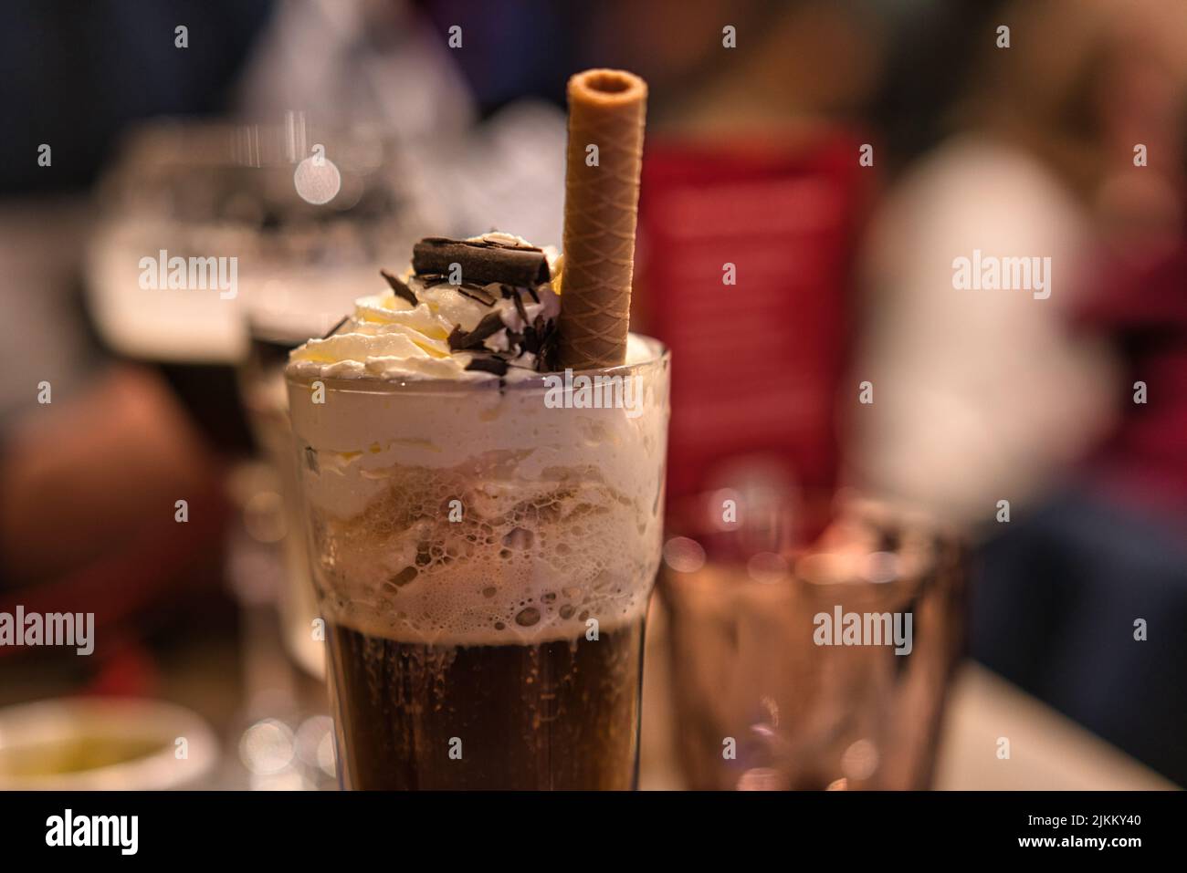 Eine Nahaufnahme eines Glases Kaffee-Cocktails mit einem Waffelröhrchen auf verschwommenem Hintergrund Stockfoto