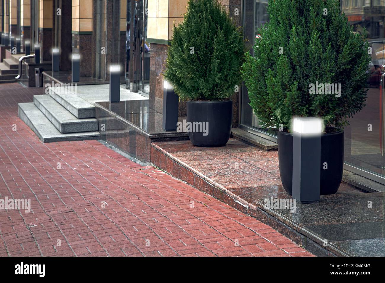 Gehweg aus Steinfliesen entlang Gebäude mit Schwellen und Stufen mit Eingängen zu Geschäften mit Granit mit schwarzen dekorativen Straßenglant gesäumt Stockfoto