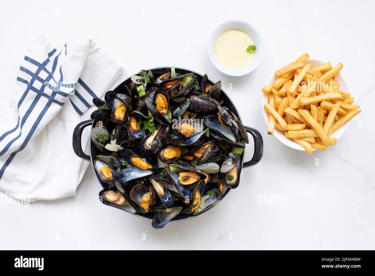 Eine Draufsicht auf belgische Muscheln mit Pommes Frites und Sauce auf einem weißen Marmortisch Stockfoto