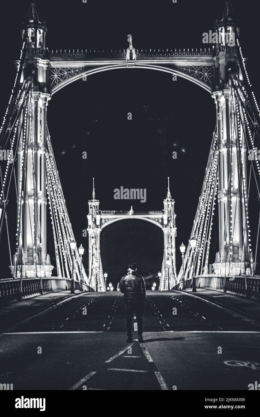 Eine vertikale Aufnahme eines Mannes, der in der Nähe der Albert Bridge in London, England, Großbritannien, steht Stockfoto