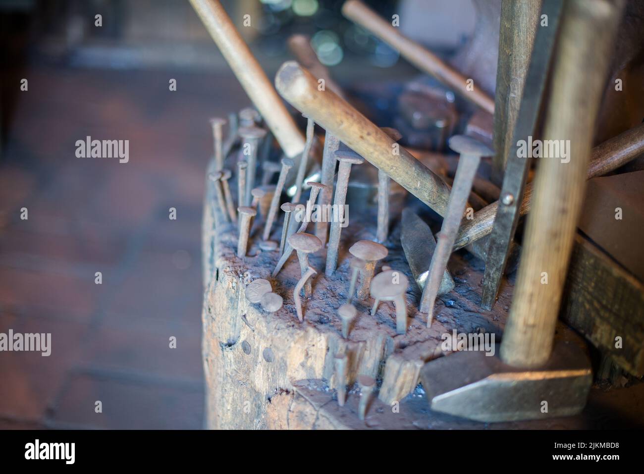 Ein Nahaufnahme von alten Nägeln und Hämmern auf einem Holzstumpf in der Schmiede Stockfoto