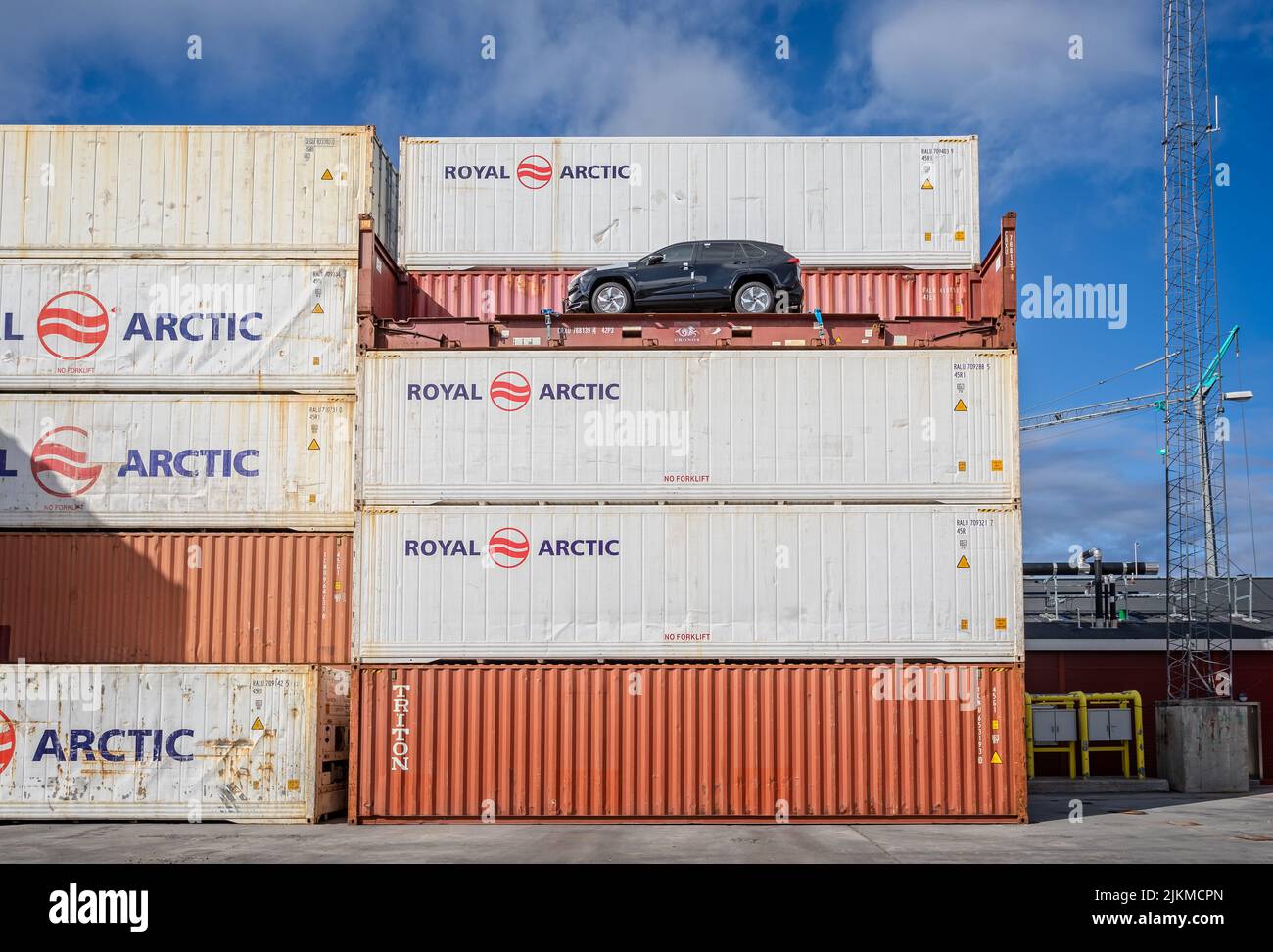 Stapel von roten und weißen Containern mit schwarzem Auto auf offenem Container auf dem Containerstapel in Sisimiut, Grönland, am 16. Juli 2022 Stockfoto