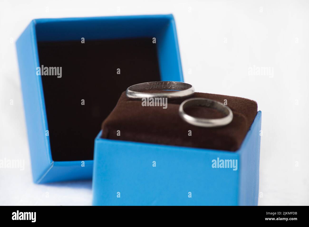 Eine Nahaufnahme von ein paar Eheringen in einer blauen Schmuckschatulle, isoliert auf weißem Hintergrund Stockfoto