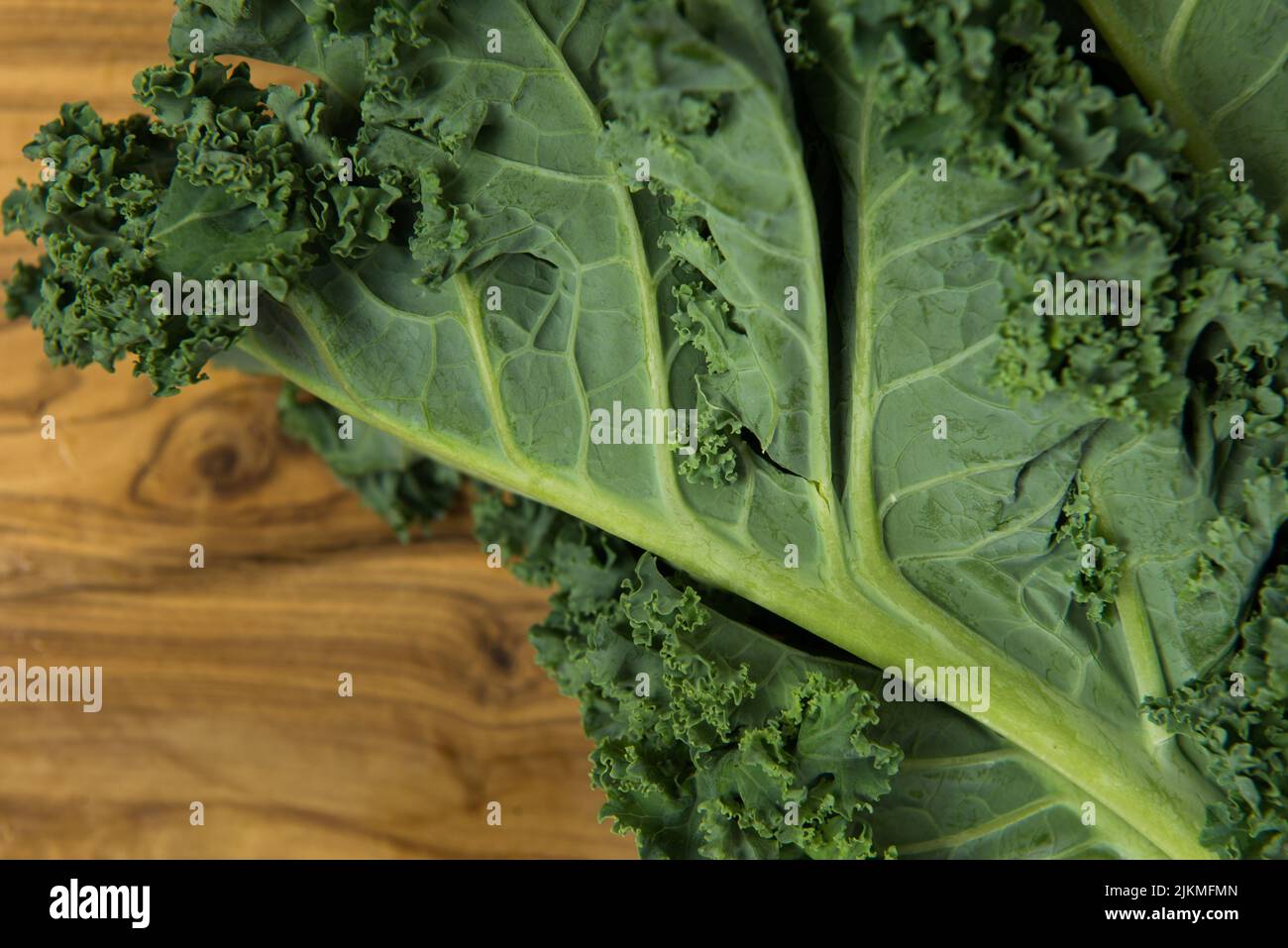 Frischer Bio-Grünkohl auf körnigem Holzhintergrund. Stockfoto