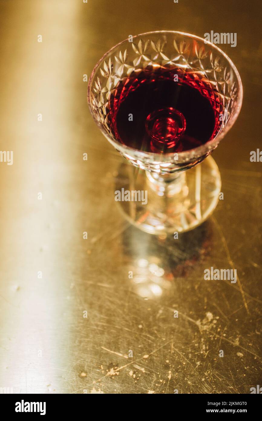 Rotwein aus geschliffenem Kristallglas auf einem Tisch aus Metallic-Gold Stockfoto