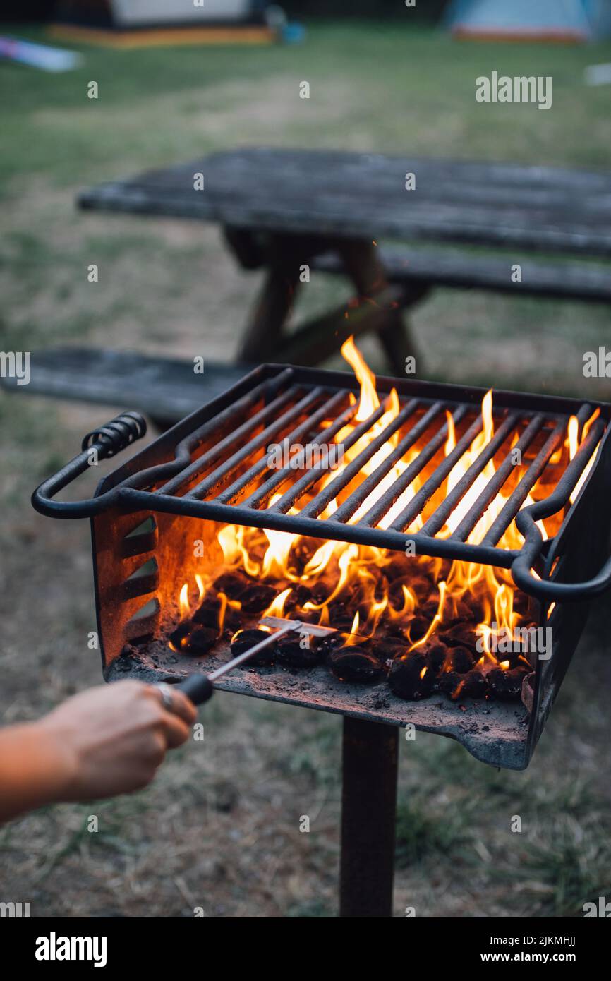 Eine vertikale Aufnahme einer brennenden Flamme in einem Grillofen im Freien neben einem Picknicktisch. Stockfoto