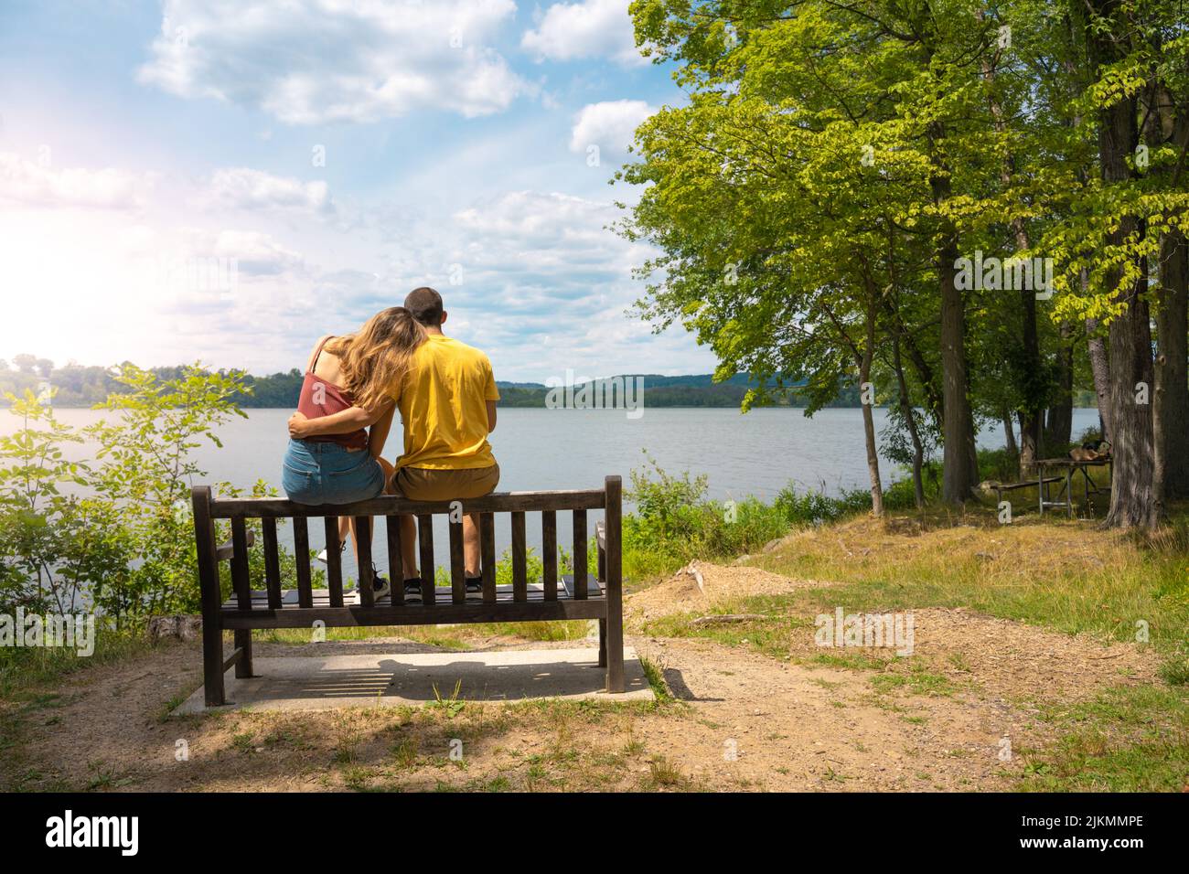 Im Sommer kuschelte sich ein junges, liebevolles Paar auf einer Bank in einem See. Stockfoto