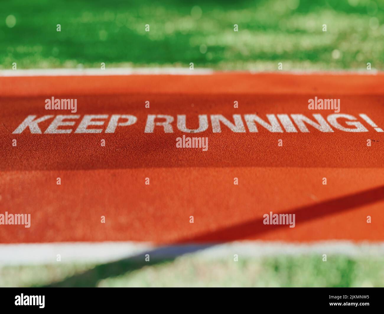 Ein „ Keep Running“-Schriftzug auf einer roten Fläche in einem grünen Feld Stockfoto