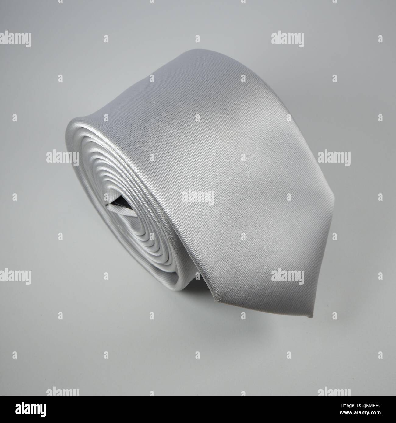 Eine Nahaufnahme eines eleganten gerollten grauen Krawatten isoliert auf weißem Hintergrund Stockfoto