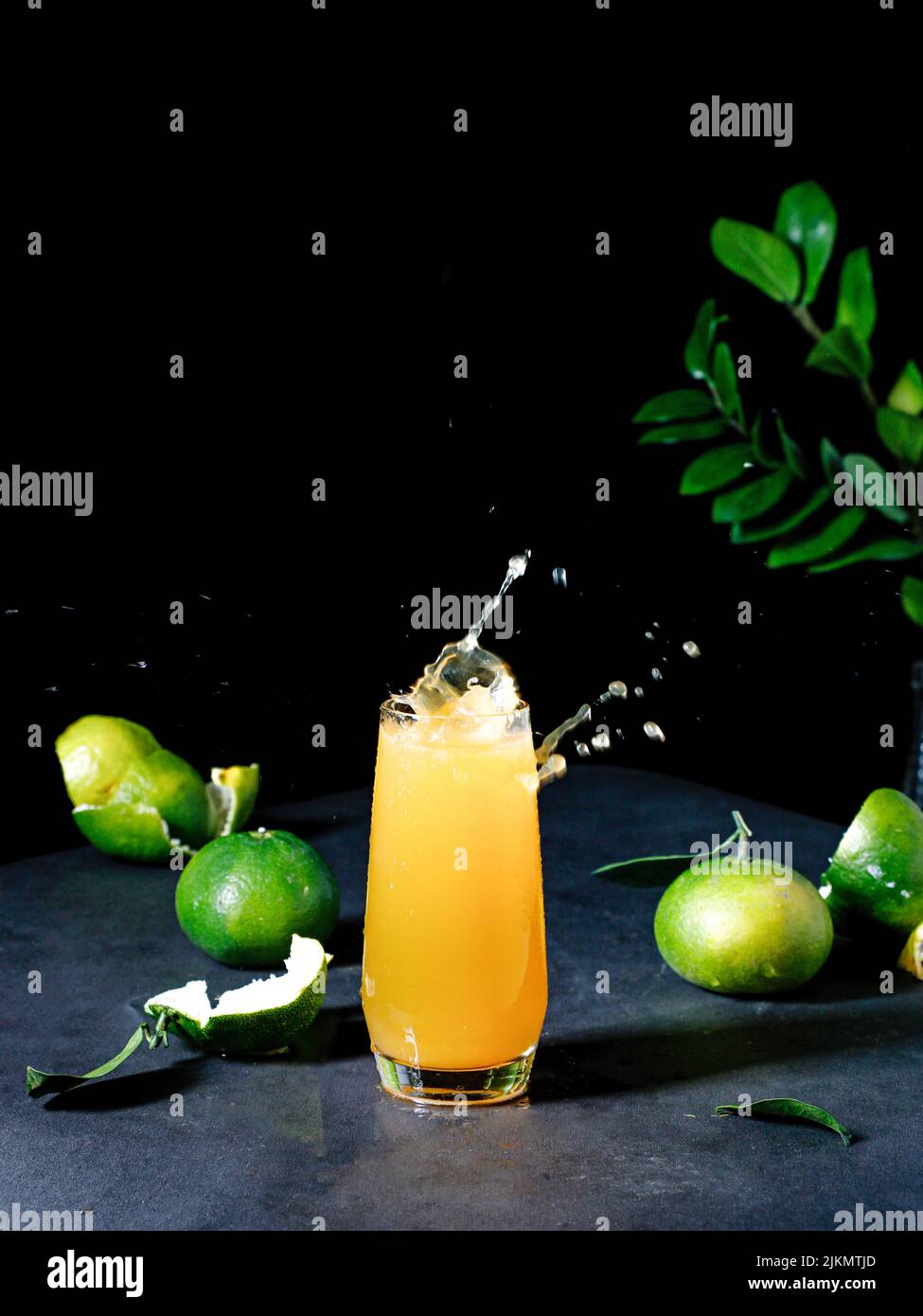Eine vertikale Aufnahme des Mandarinensaftes und der grünen Blätter Stockfoto