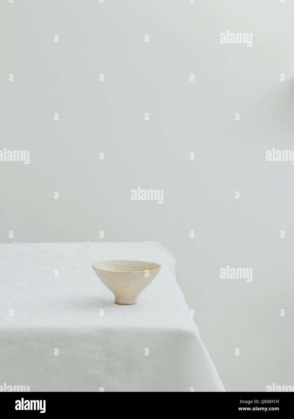 Ein ästhetischer Blick auf eine minimalistische Schale auf einem Tisch mit weißer Tischdecke Stockfoto