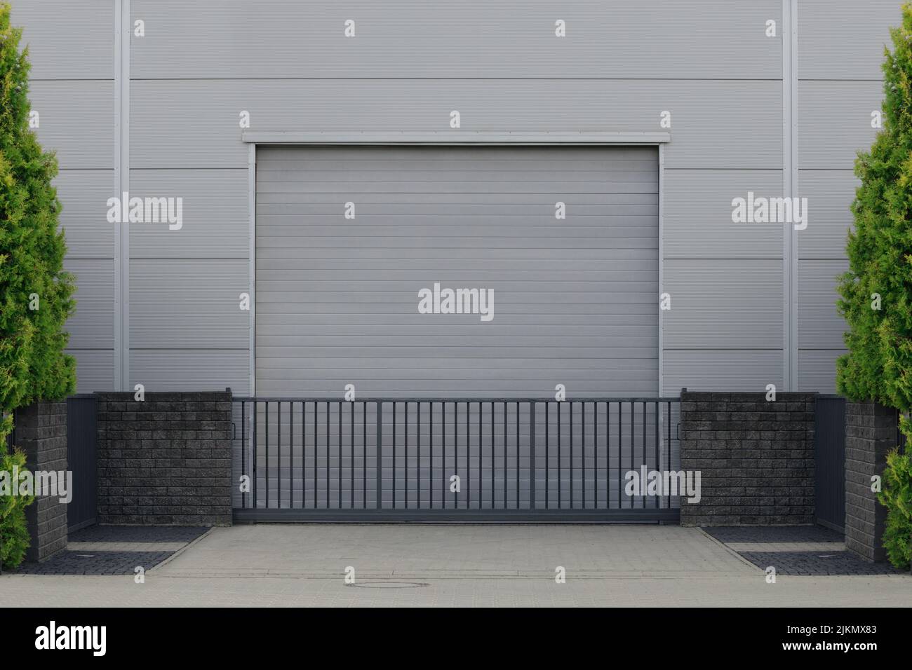 Rollentür oder Rollladen mit Anwendung in Fabrik, Lager oder Hangar. Draußen Bäume an den Seiten Stockfoto