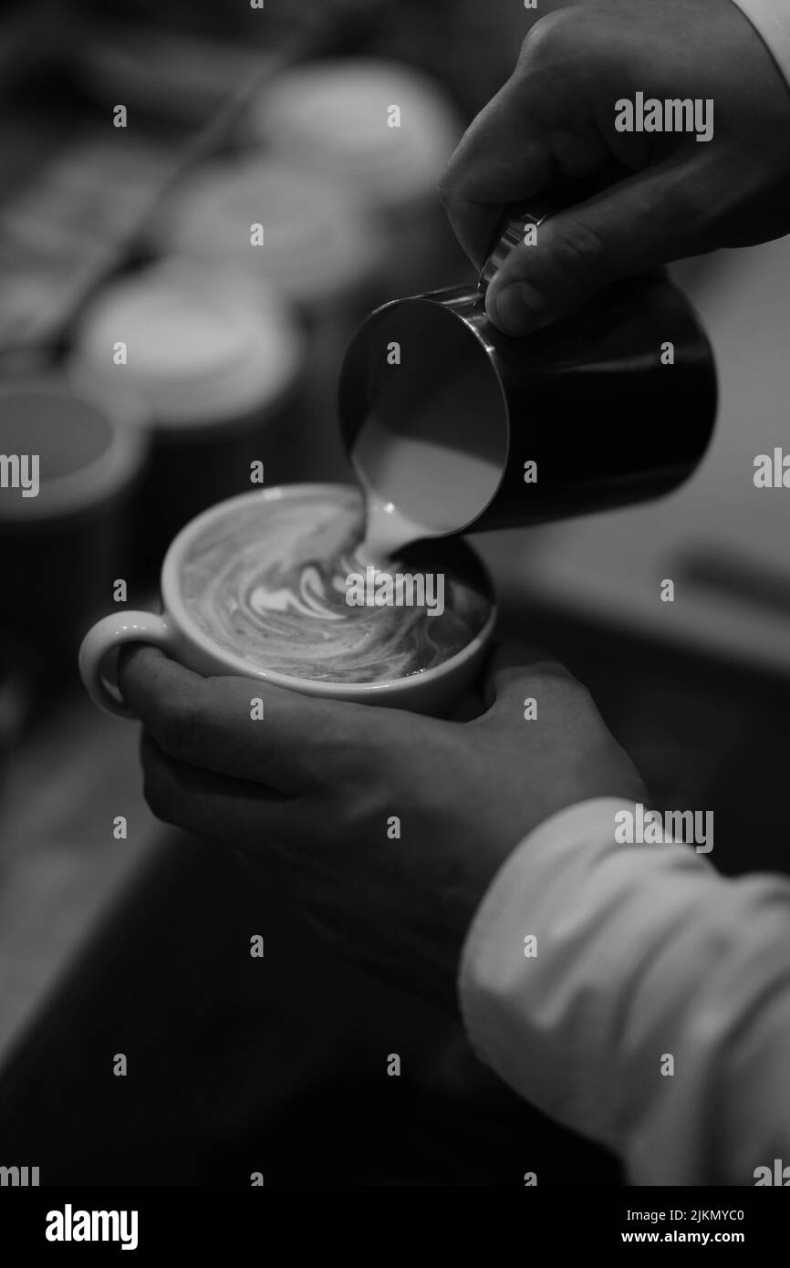 Eine Graustufenaufnahme eines Barkeeps, der das Kaffeegetränk im Café zubereitet Stockfoto