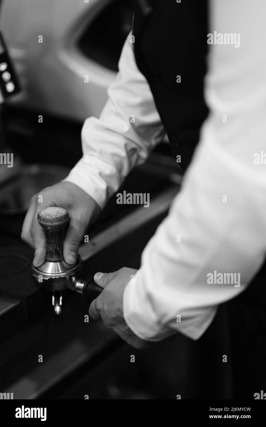 Eine Graustufenaufnahme eines Barkeeps, der das Kaffeegetränk im Café zubereitet Stockfoto