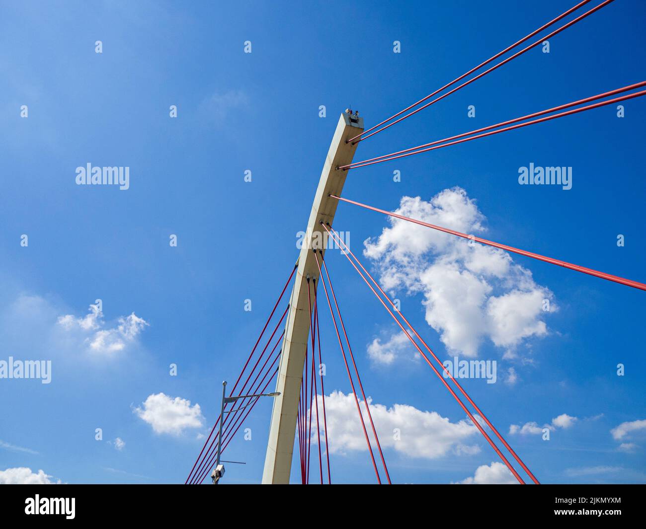 Ein niedriger Winkel aus roten Kabeln und einer Metallstruktur vor einem hellen, bewölkten Himmel Stockfoto