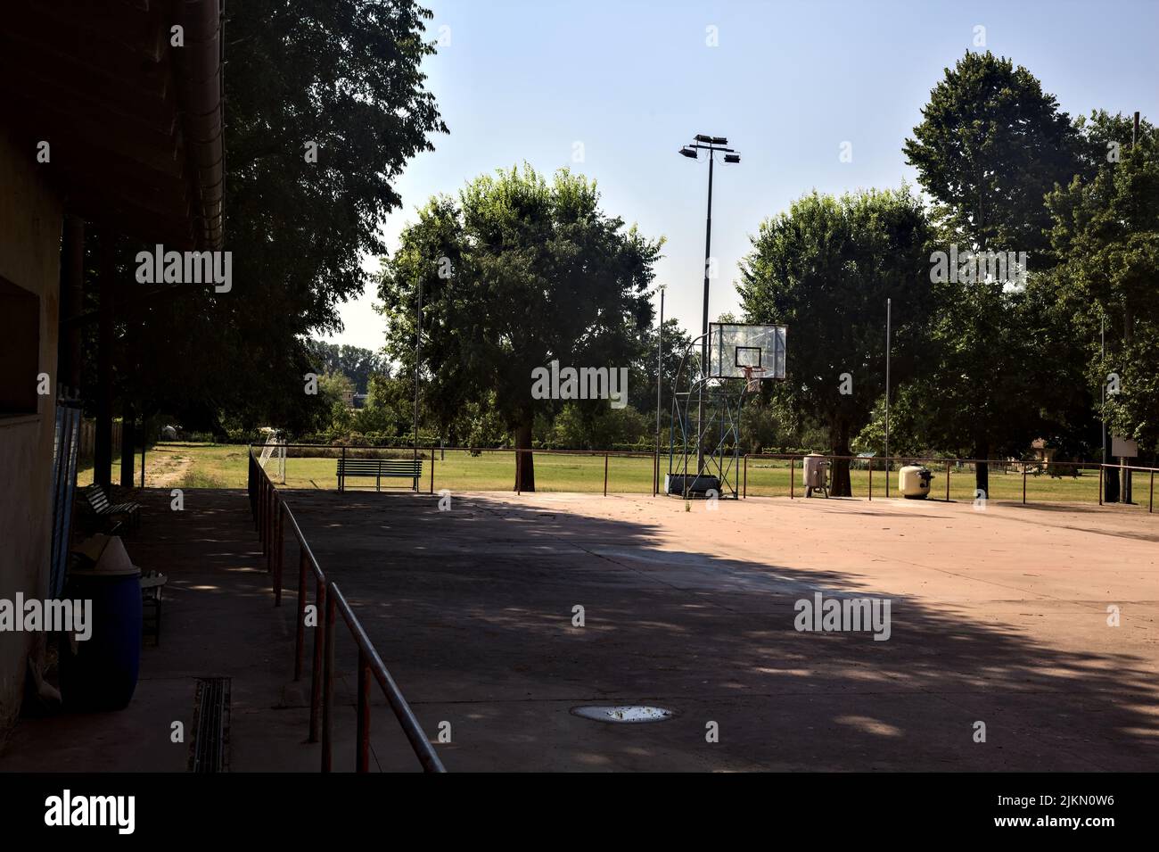 Leerer Basketballplatz, an einem sonnigen Tag von einer Schiene begrenzt Stockfoto