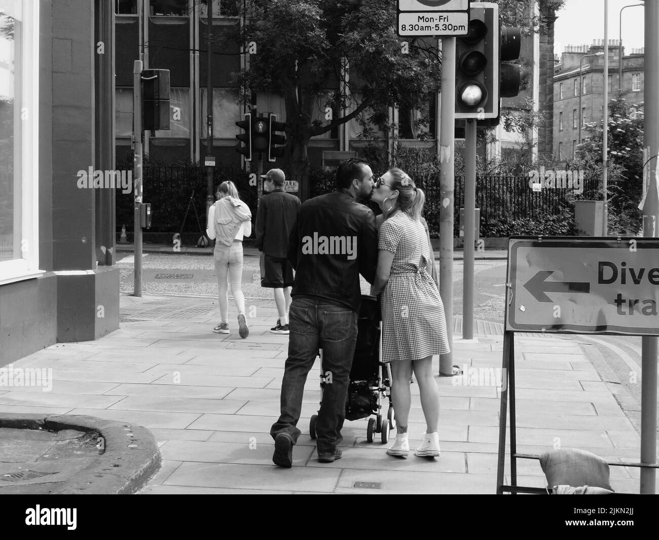 Eine Graustufenansicht einer schönen glücklichen Familie, die sich auf der Straße in Edinburgh, Andorra, küsst Stockfoto