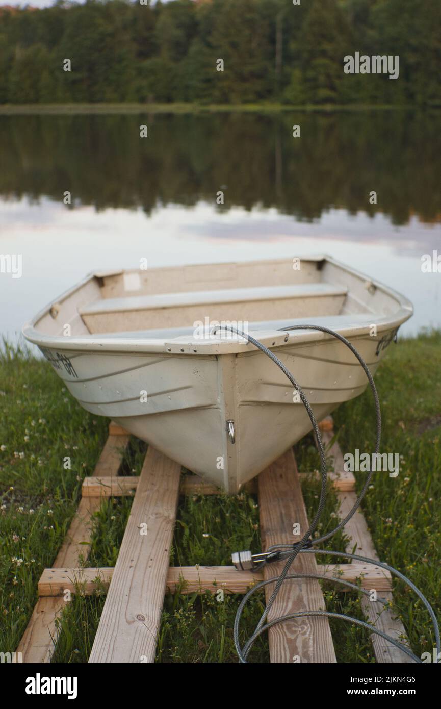 Eine selektive Fokusaufnahme des Ruderbootes, das auf dem Grasland in der Nähe des Sees angedockt war Stockfoto