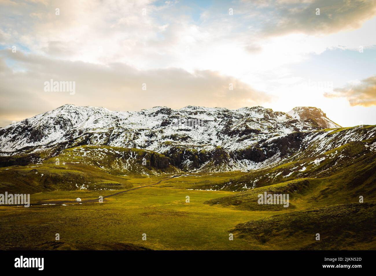 Eine schöne Landschaftsansicht von verschneiten Bergen auf Grasland mit einem bewölkten Himmel in Rangarping, Eystra Southern, Island Stockfoto