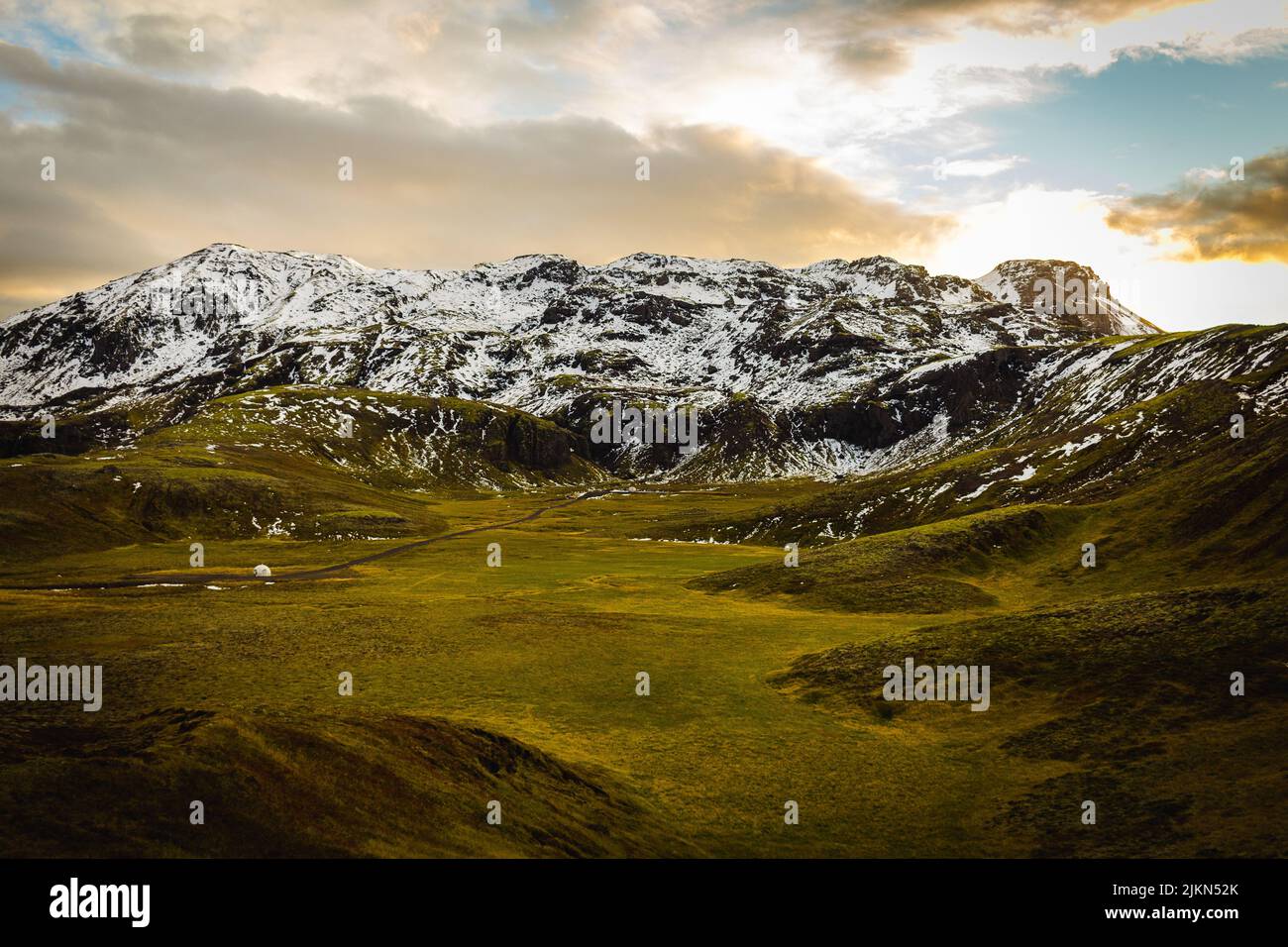 Eine schöne Landschaftsansicht von verschneiten Bergen auf Grasland mit einem bewölkten Himmel in Rangarping, Eystra Southern, Island Stockfoto