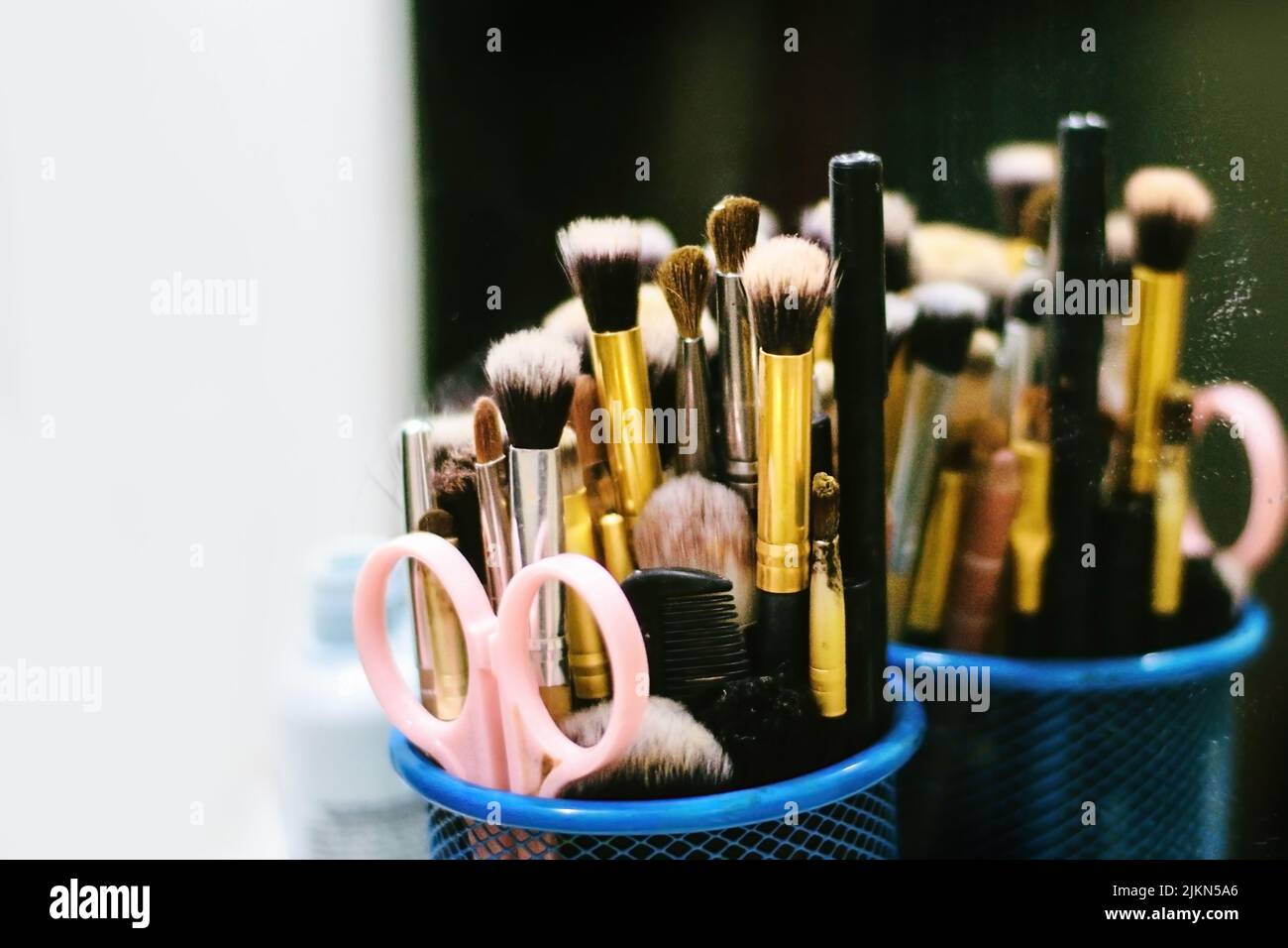 Eine Nahaufnahme eines Sets von Make-up-Bürsten, Scheren und Kamm, die auf dem Spiegel reflektiert werden Stockfoto