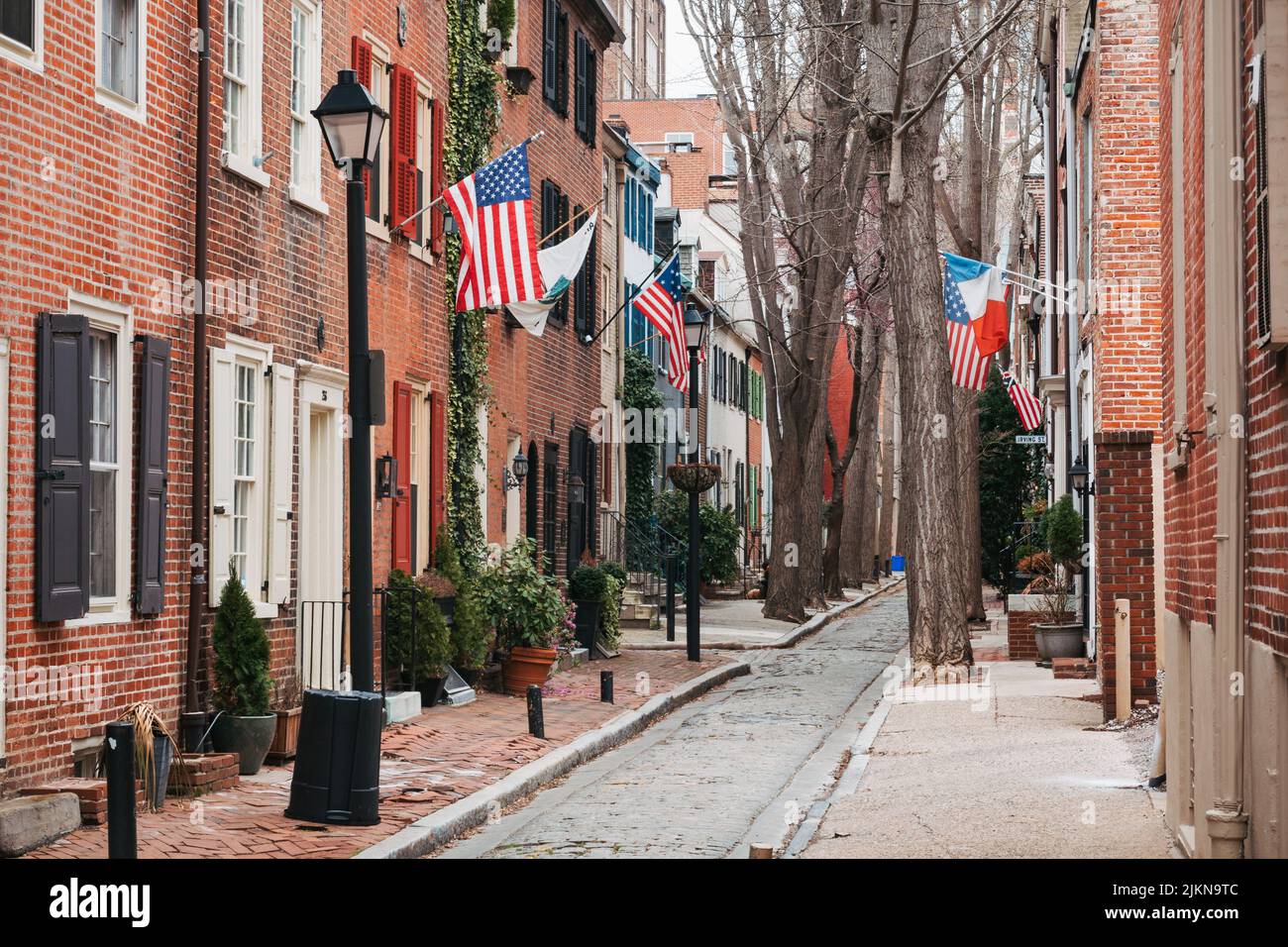 Amerikanische und französische Flaggen aus gemauerten Reihenhäusern in einer engen Straße in Philadelphia, USA Stockfoto