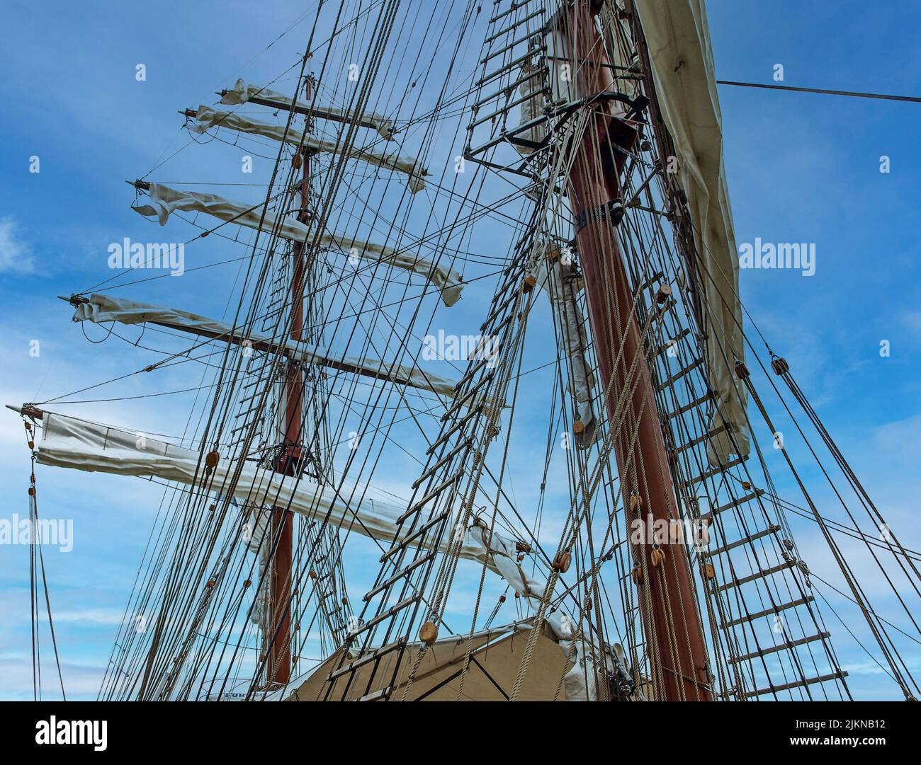 Der hohe Mast eines alten Segelschiffes mit einer Schiffsleiter im blauen Himmel Hintergrund Stockfoto