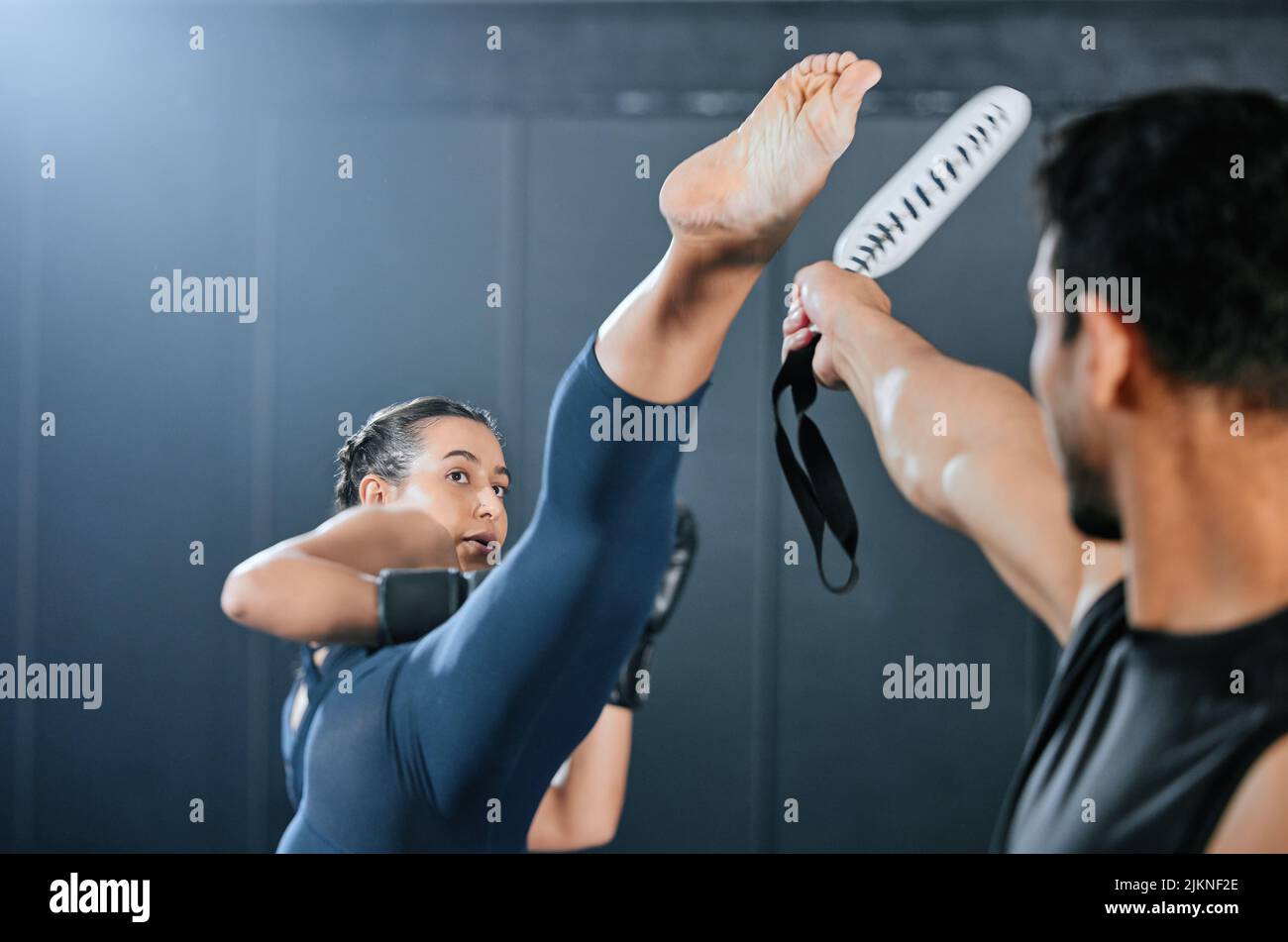 Fit, aktiv und starke Frau macht Bewegung, Training und Training während Kickboxen mit Trainer in einem Fitnessstudio. Selbstbewusste weibliche Sportlerin tritt, tut Stockfoto