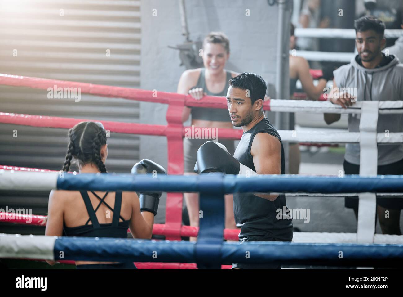 Zwei junge professionelle Boxer bereiten sich darauf vor, im Boxring zu kämpfen und ihre Fähigkeiten zu verbessern. Starke und fokussierte Athleten trainieren gemeinsam im Fitnessstudio Stockfoto
