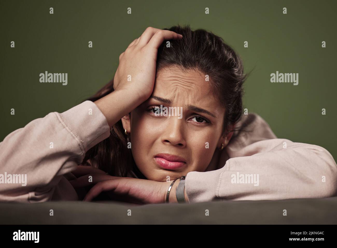 Ich bin mit allem fertig. Beschnittenes Porträt einer attraktiven jungen Frau, die vor grünem Hintergrund weint. Stockfoto