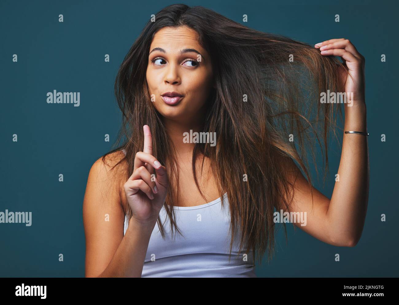 Neugier, der Motor des Erzielens. Studioaufnahme einer schönen jungen Frau mit dem Finger nach oben, der vor blauem Hintergrund posiert. Stockfoto