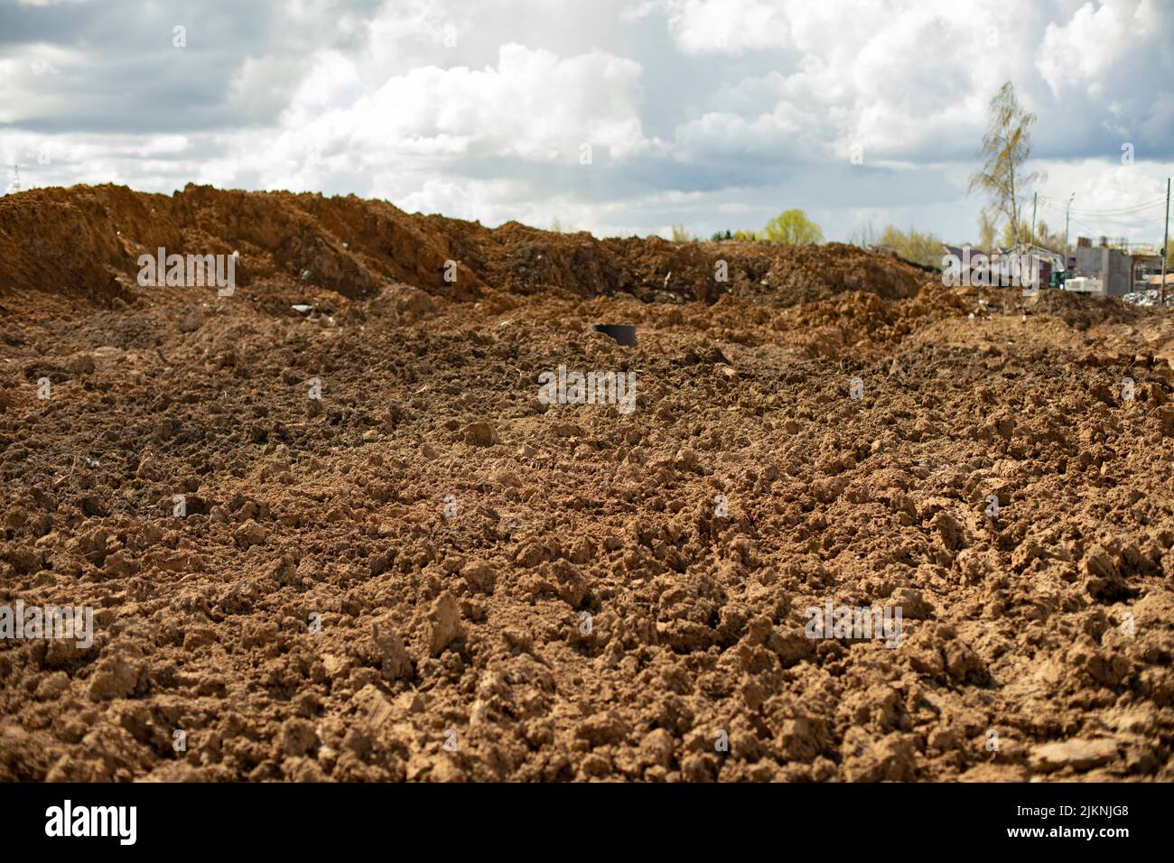 Ausgegrabener Boden. Ausgegrabene Erde. Konstruktionsdetails. Schaffung von Böschung für die Straße. Viele Baustoffe. Stockfoto