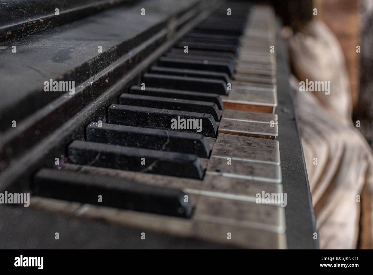 Ein gebrochenes Vintage-Klavier mit schmutzigen Klavierschlüsseln in einem verlassenen Lagerhaus Stockfoto