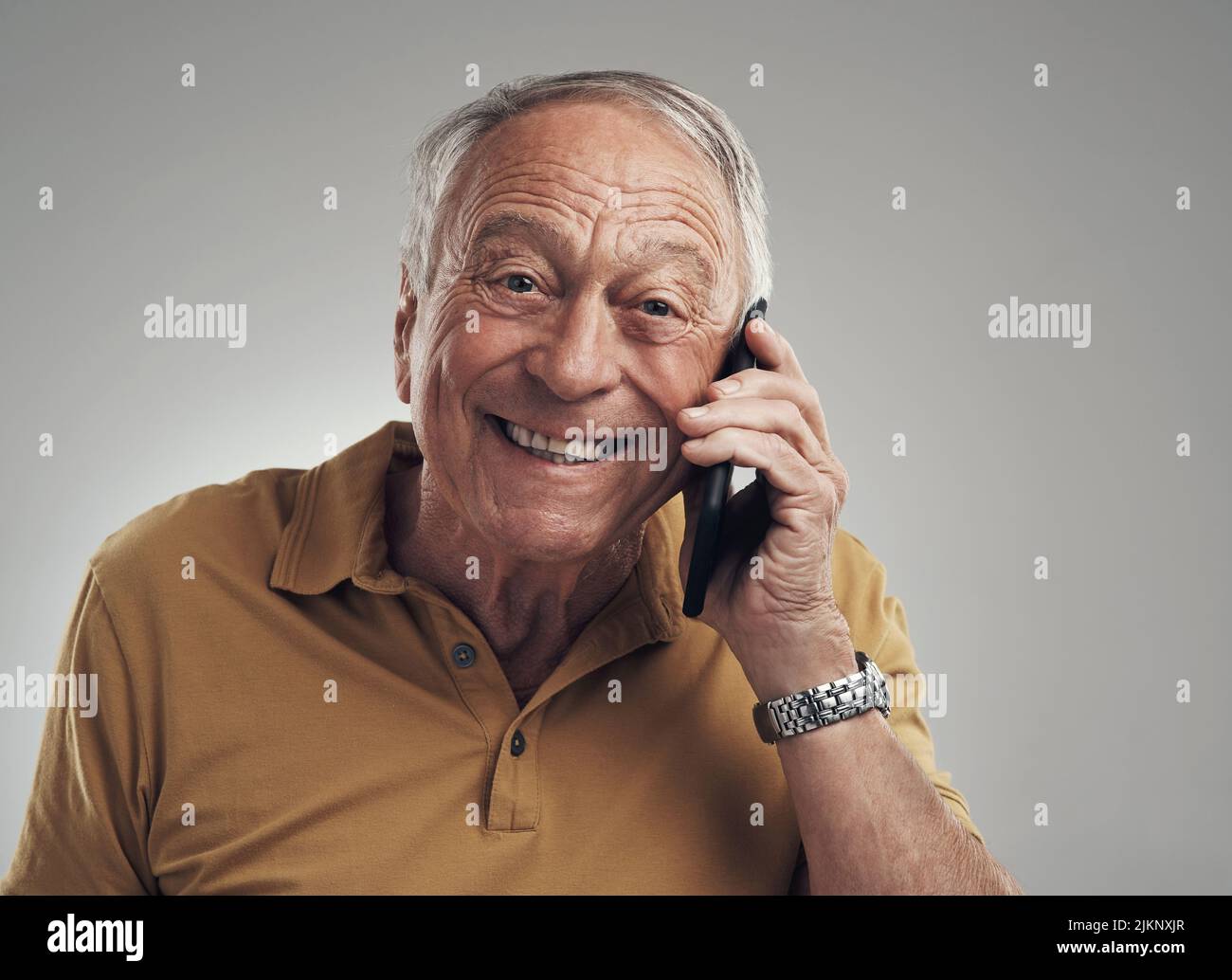 Ein Anruf von dem, den ich liebe. Studioaufnahme eines älteren Mannes, der sein Handy vor grauem Hintergrund benutzte. Stockfoto