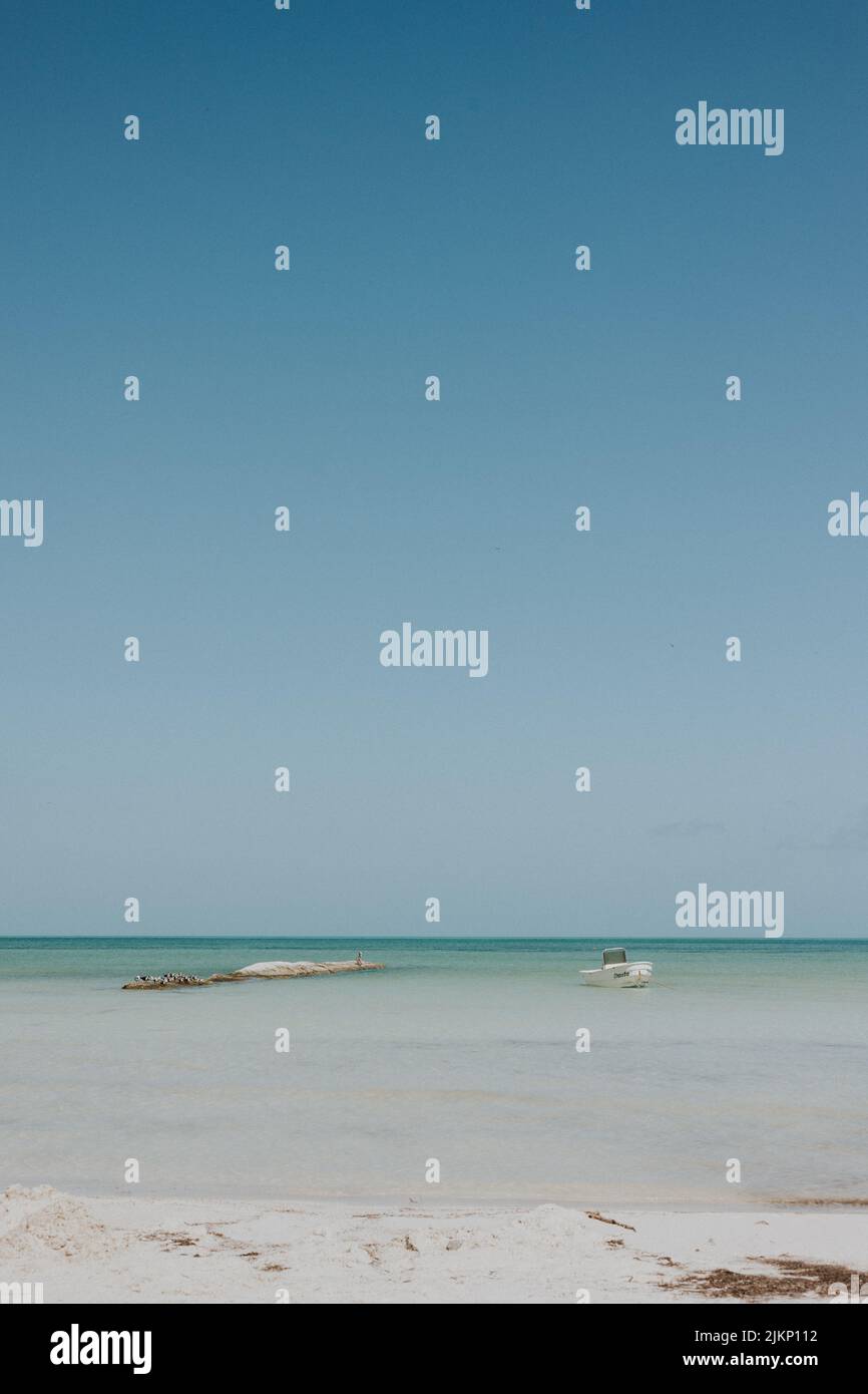 Eine vertikale Aufnahme eines Sandstrandes mit kristallklarem Meer unter dem blauen Himmel Stockfoto