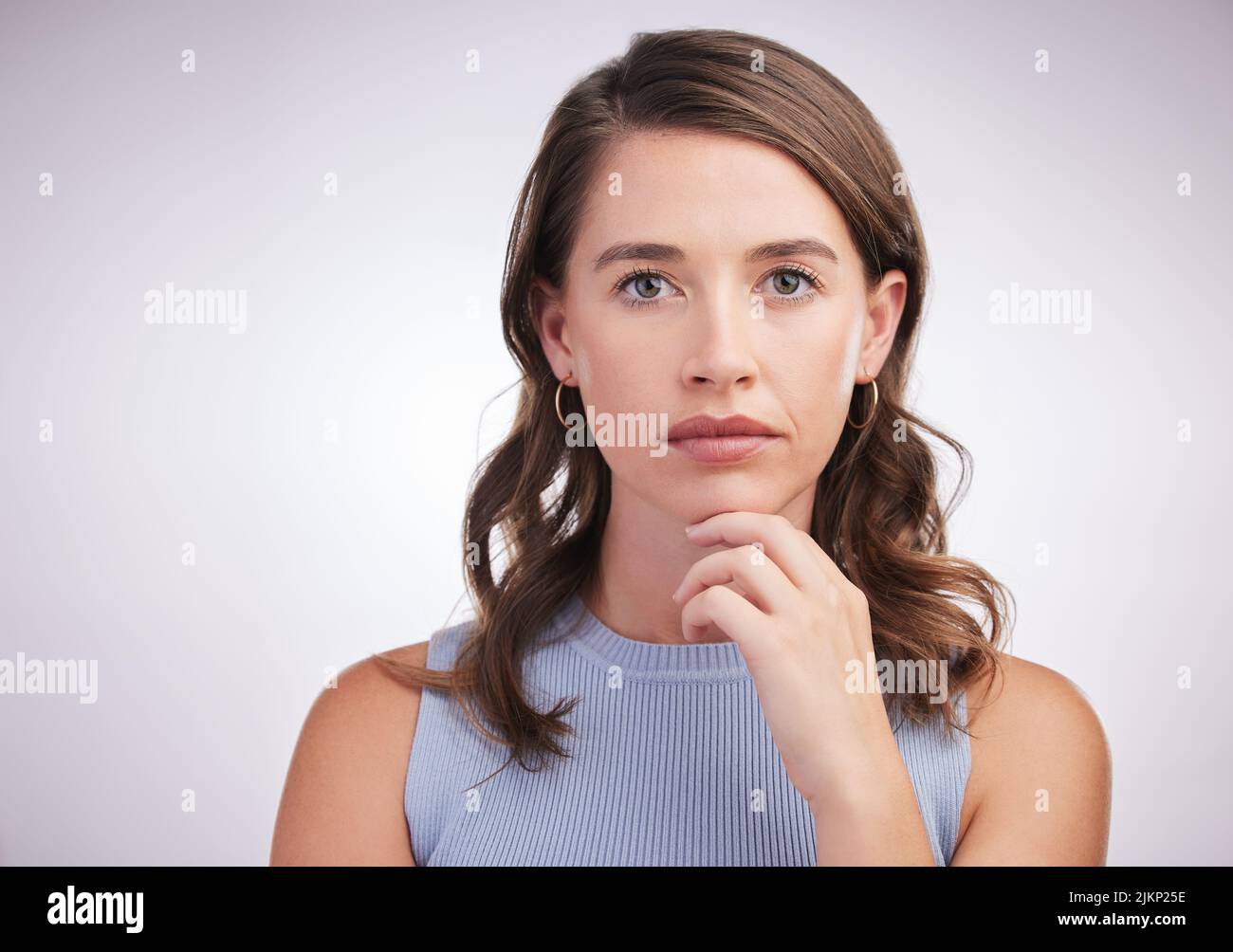 Ich bin mir immer noch ein wenig unsicher... Studioportrait einer jungen Frau, die vor grauem Hintergrund nachdenklich aussieht. Stockfoto