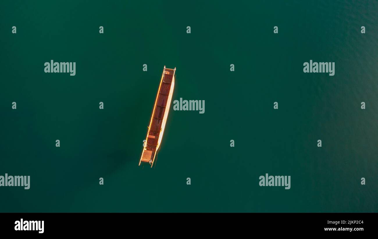 Eine vertikale Luftaufnahme eines kleinen Holzbootes auf einem grünen Gewässer Stockfoto