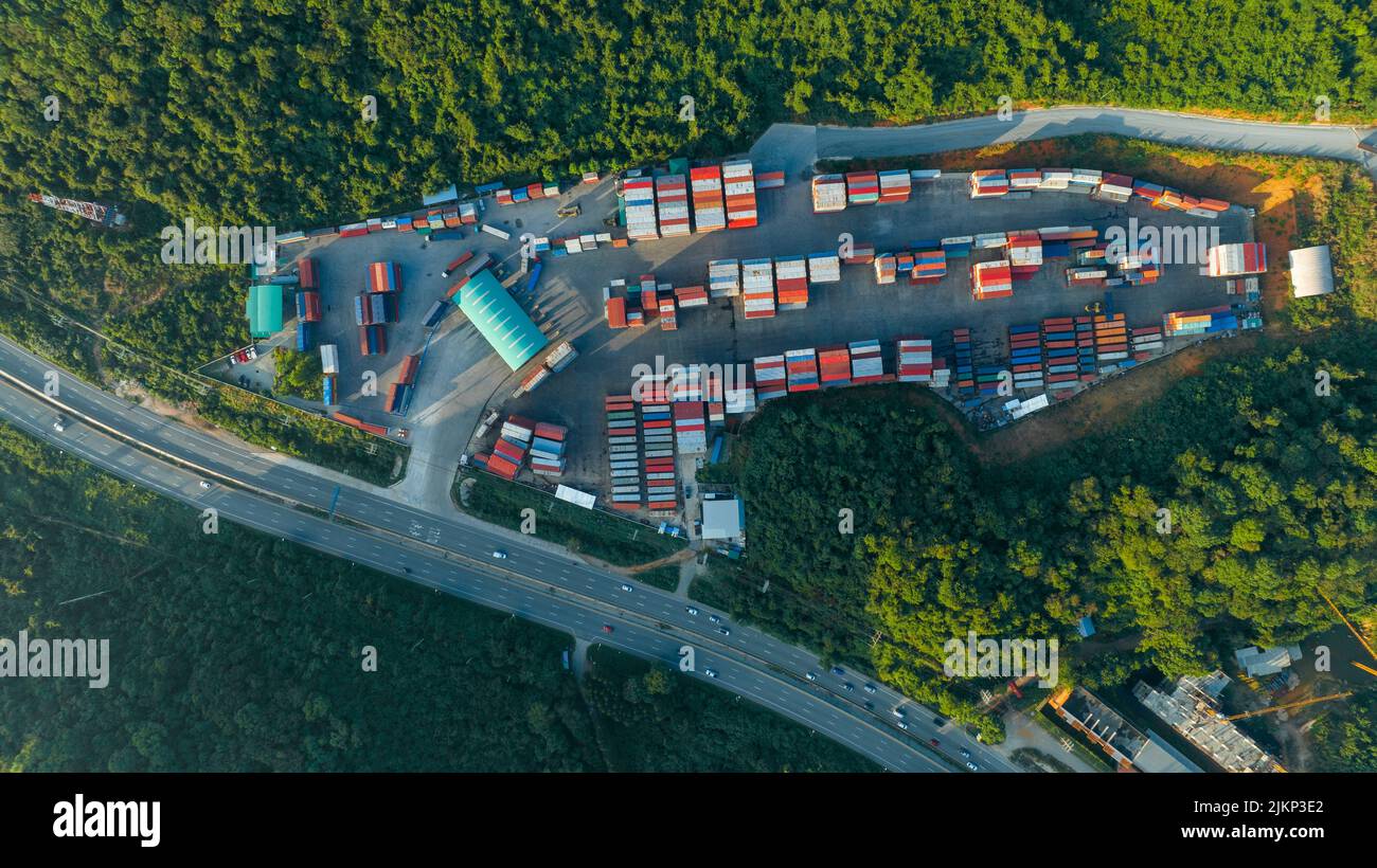 Die Cargo Container Werft neben der Straße und umgeben von Bergen, Gabelstapler und Fracht am Depot Arbeitslast entladen Transport und Transport Stockfoto