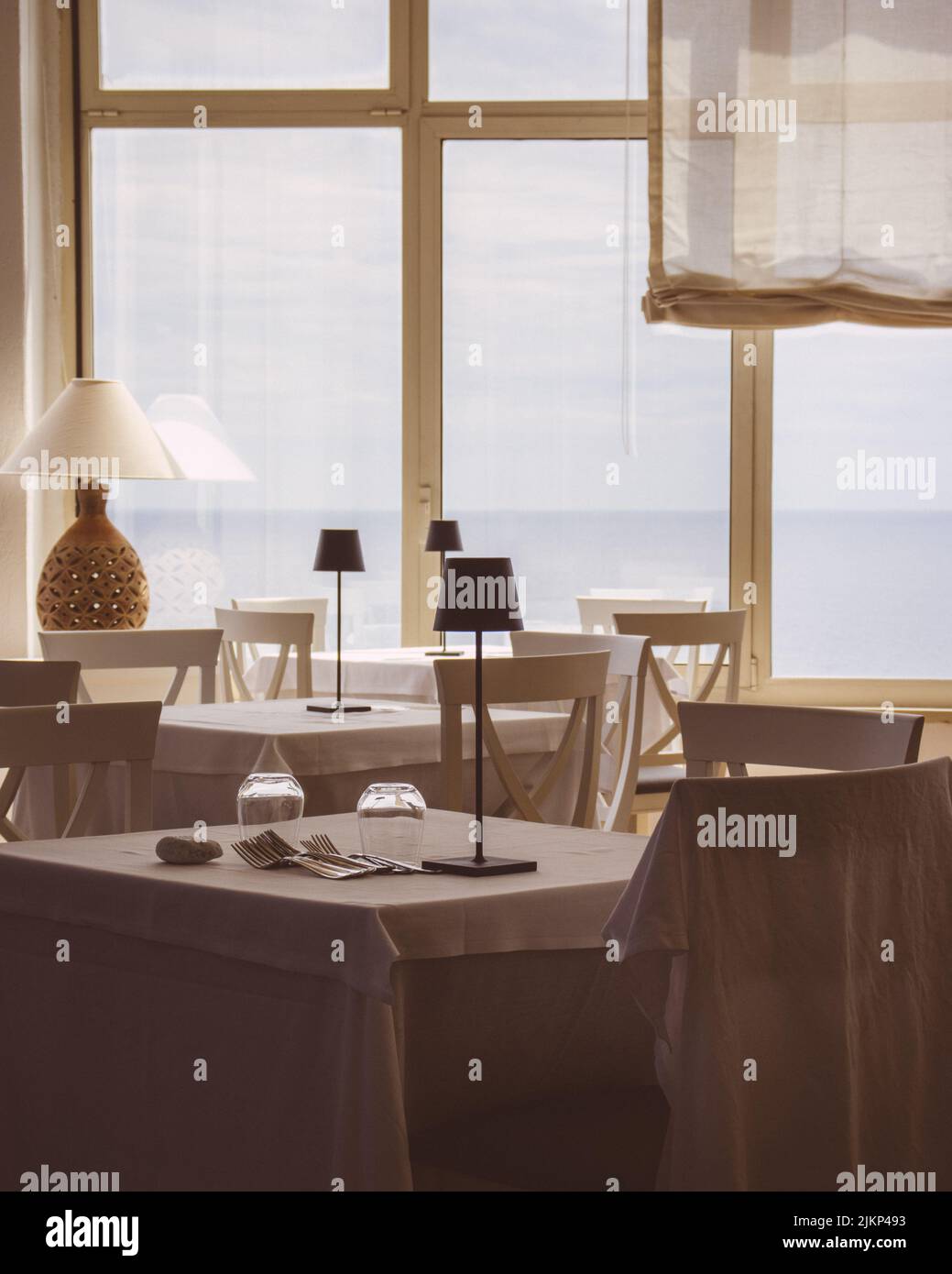 Eine schöne Aufnahme der Inneneinrichtung von hellen Restauranttischen mit Pro Table-Lampen und Glasfenstern Stockfoto