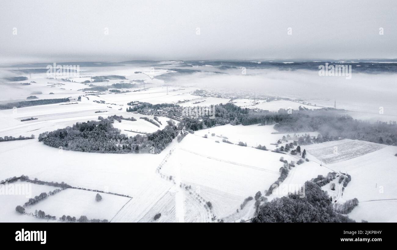 Eine Drohne schoss auf ein schneebedecktes Feld unter einem grauen nebligen Himmel Stockfoto
