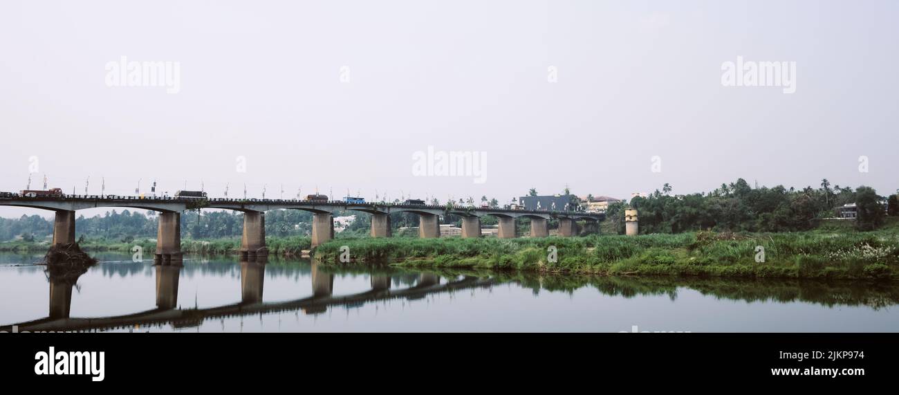 Ein Panoramablick auf die Brücke über den Fluss, umgeben von Vegetation. Stockfoto