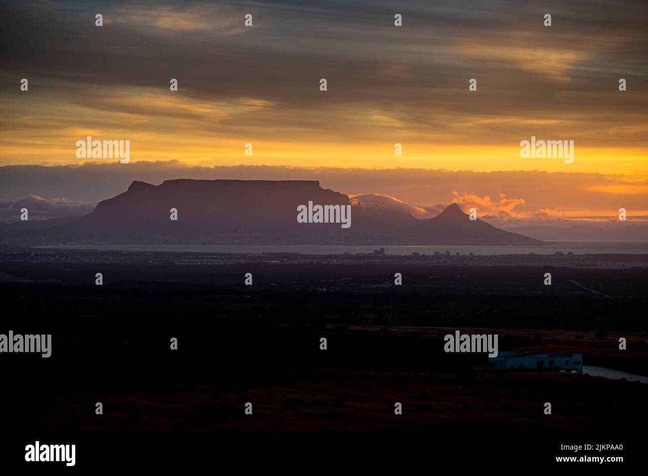 Ein atemberaubender Sonnenuntergang mit der Silhouette einer mesa unter einem bewölkten Himmel Stockfoto