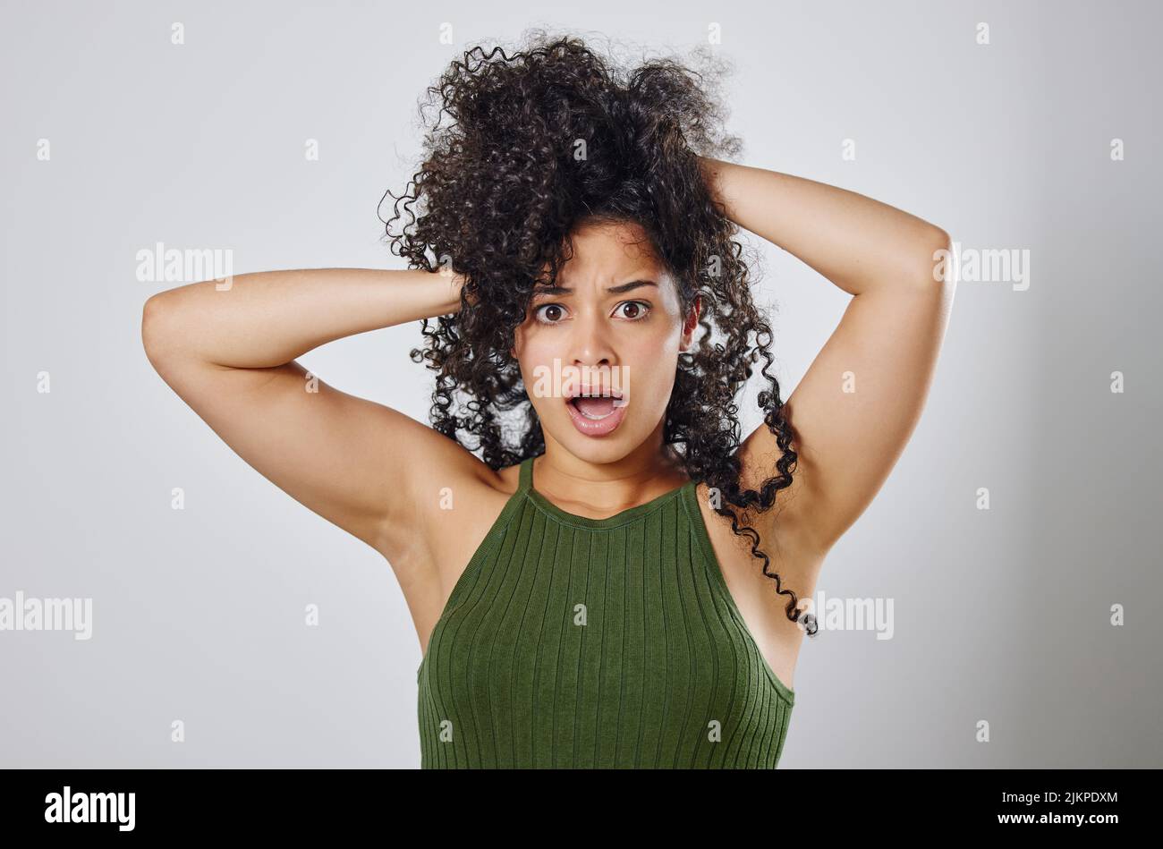 Was hast du gerade über meine Haare gesagt? Studioaufnahme einer Frau mit unordentlichen Haaren, die vor einem grauen Hintergrund posiert. Stockfoto