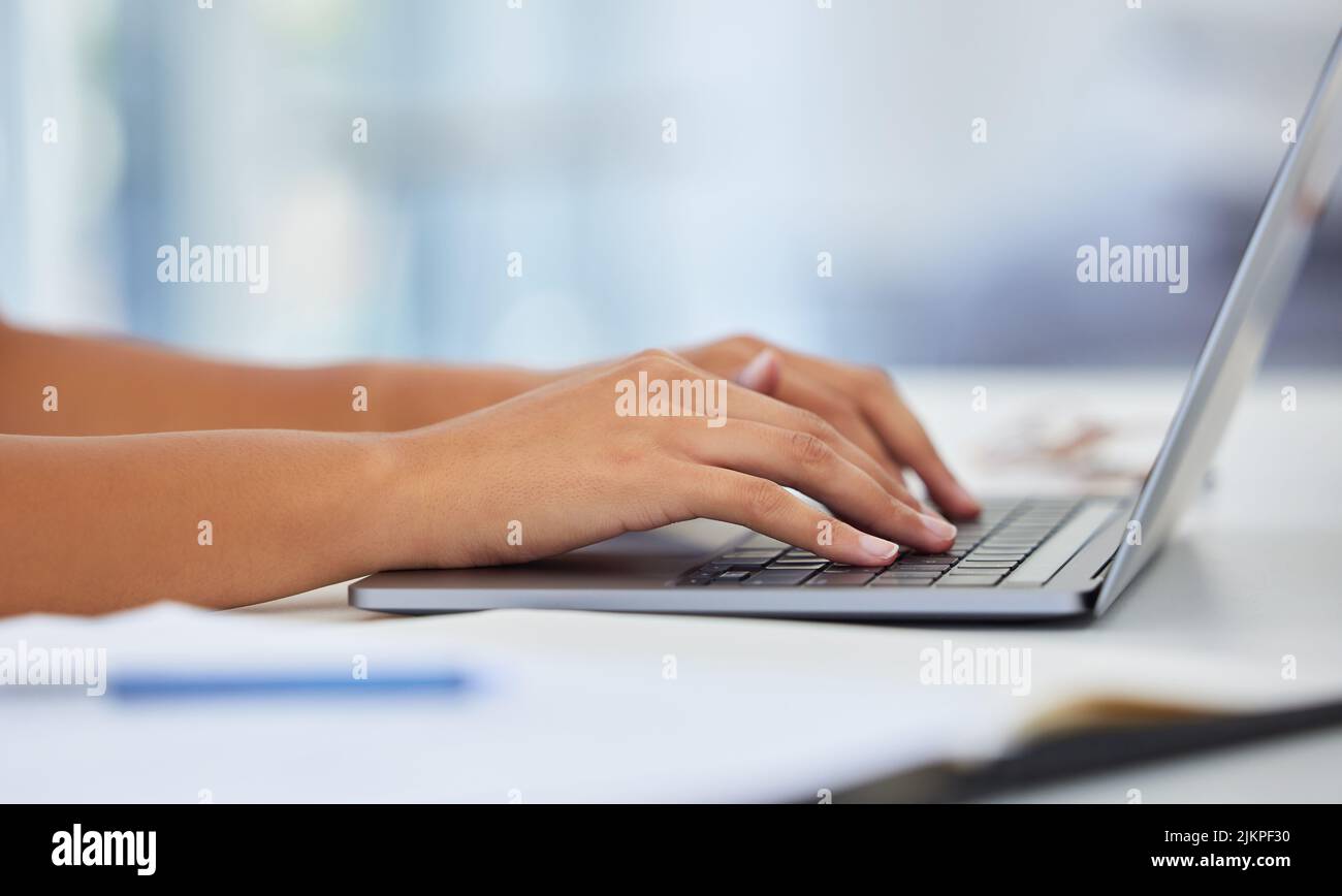 Dieser neue Laptop war eine Freude zu benutzen. Ein anonymer sitzt auf ihrem Schreibtisch und tippt auf ihrem Laptop. Stockfoto
