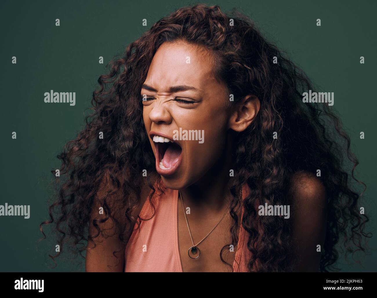 Eine attraktive und schrullige junge Frau, die vor grünem Hintergrund im Studio posiert. Stockfoto
